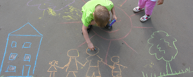 Boy drawing family with chalk