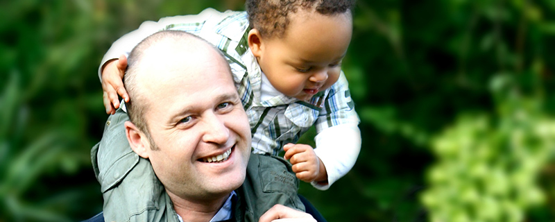 White father with african-american infant son on his shoulders