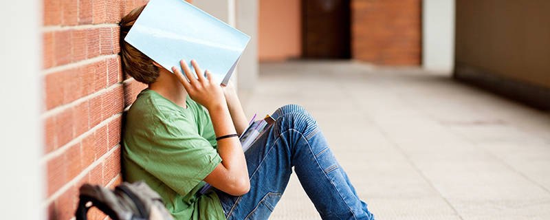 Boy with textbook over his head