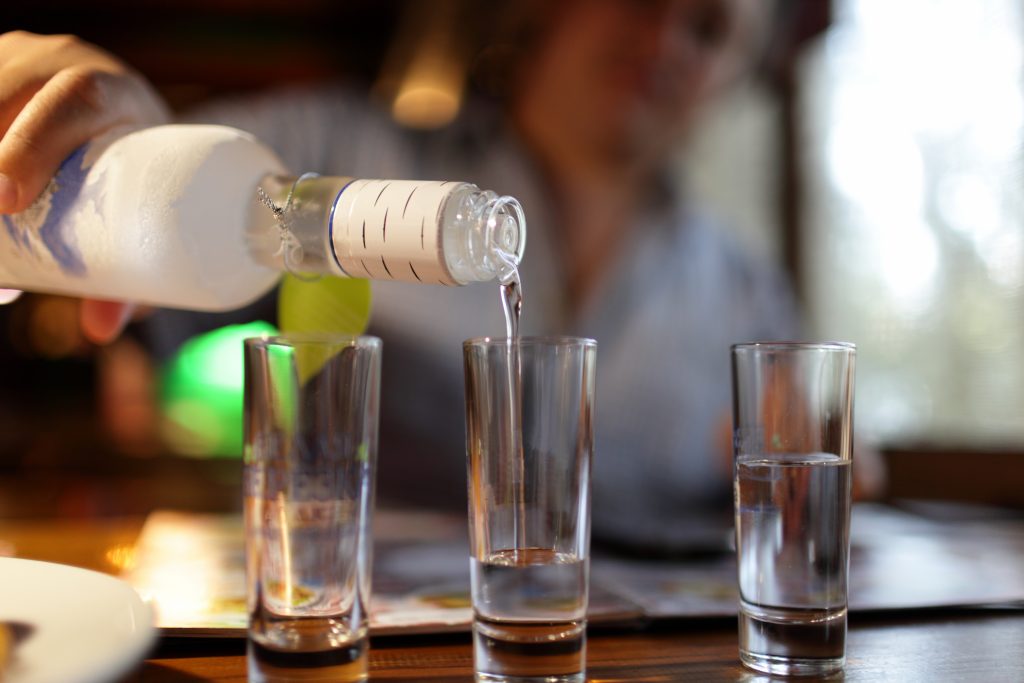 Pouring vodka into shot glasses (Shutterstock)