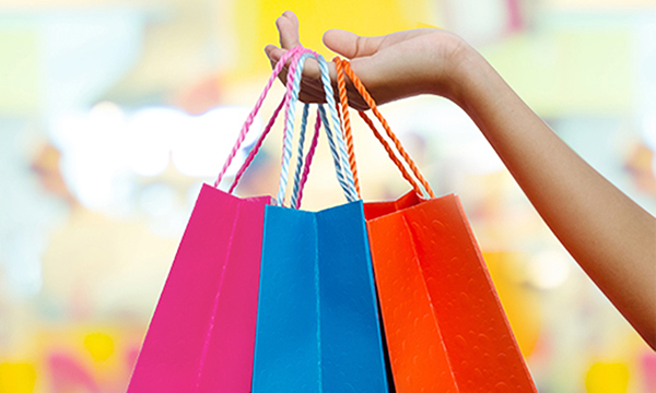 Hand holding three colorful shopping bags