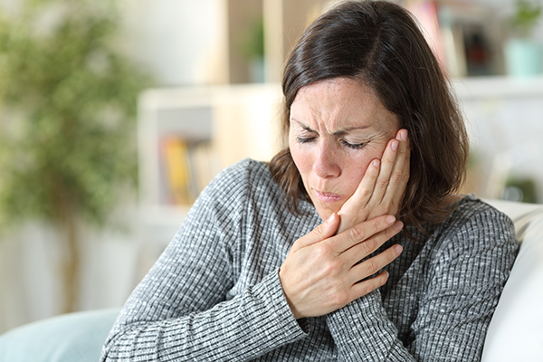 Woman holding her hand against her cheek in pain