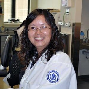 Woman smiling at camera wearing laboratory coat