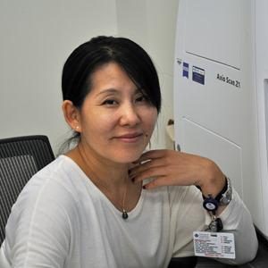 Woman smiling at the camera in front of a laboratory instrument