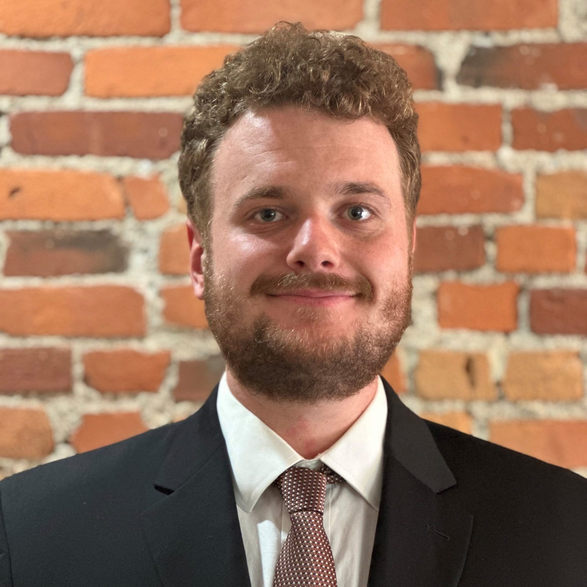 Man smiling at camera wearing suit and tie