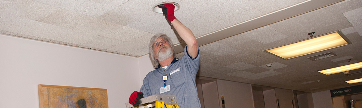 Facilities Management employee changing a lightbulb