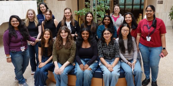 Large group of young women sitting and standing inside smiling and posing for a picture