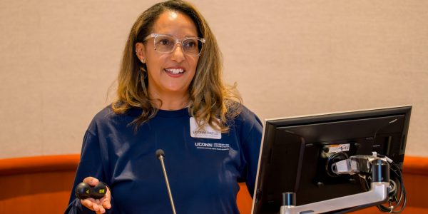 A woman wearing glasses and standing behind a podium giving a presentation