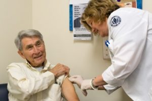 Study nurse Carlene Bartolotta applies a bandage after giving the flu shot to Nick Cesaro