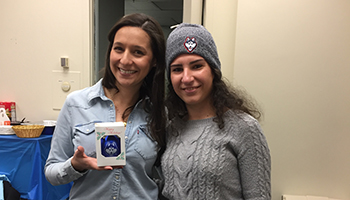 Two coworkers holding up a UConn Husky ornament