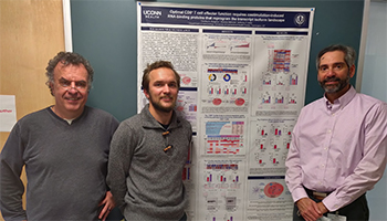 Timofey Karginov standing with two faculty in front of his poster presentation