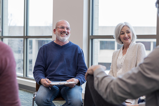 Mature adult leader of support group encourages unseen participant