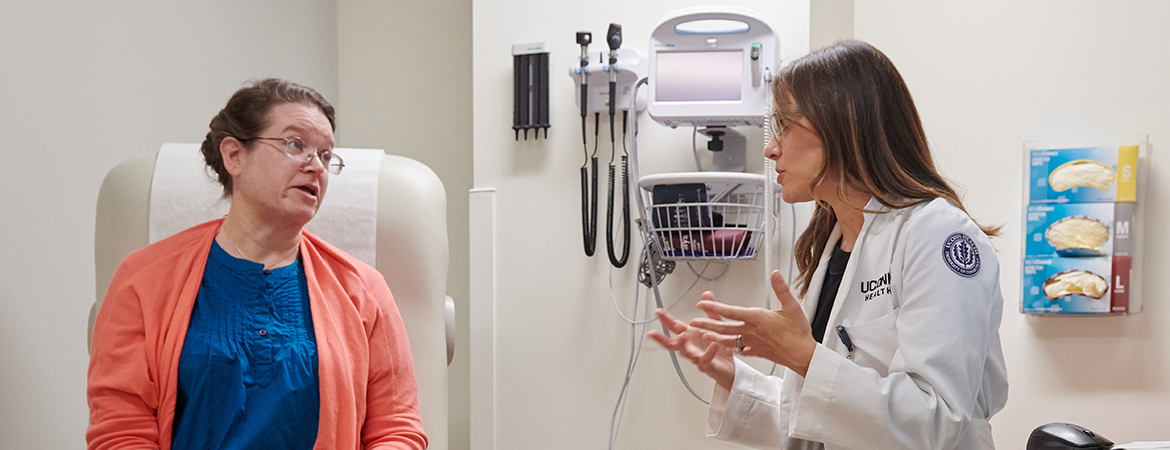Marina Creed, APRN, talks to a female patient in an exam room