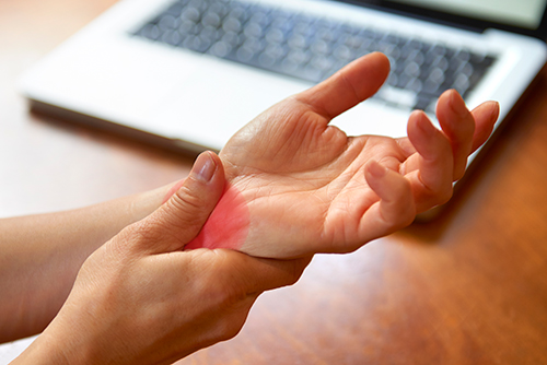 Woman massaging painful wrist at work repetitive strain injury