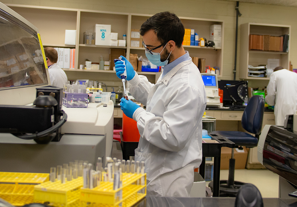 Lab worker standing pipetting into a test tube