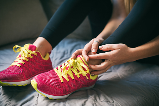 Young athletic woman holding injured ankle