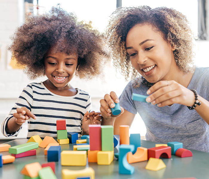Toddler girl and mother playing with colorful wooden blocks