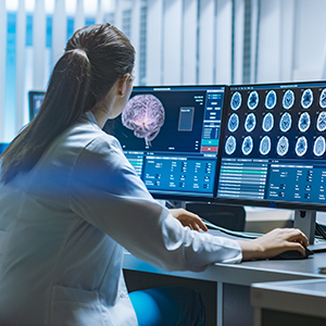 Provider looking at scans of the brain on two monitors