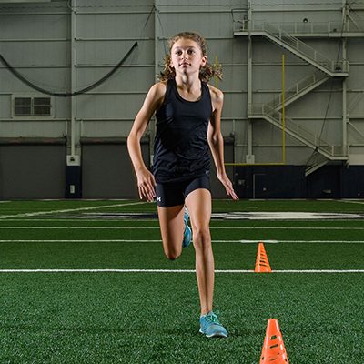 Teenage girl running on an indoor field