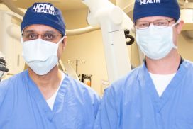 Drs. Ketan Bulsara and Daniel Roberts in surgical masks and scrubs in the operating room
