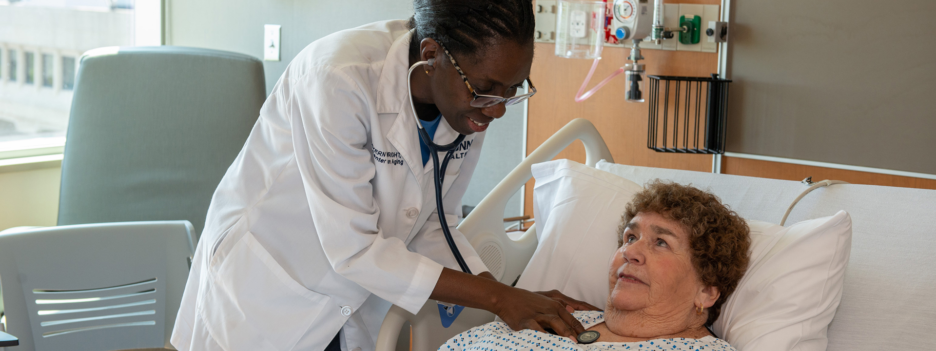 Lavern Wright, M.D., examining a patient laying in a hospital bed
