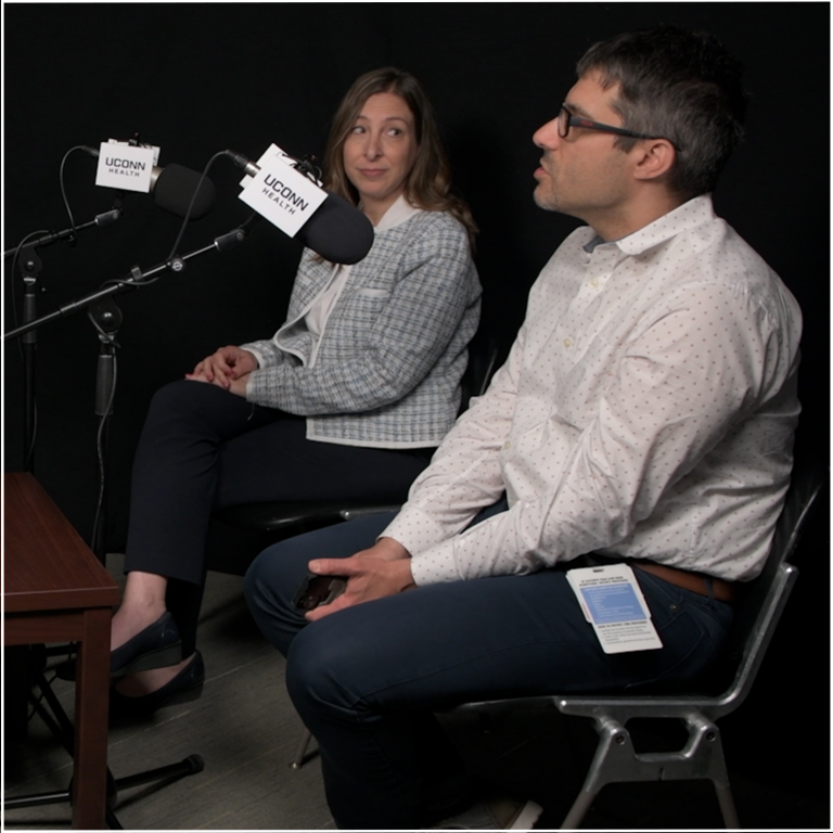 Drs. Melissa Held and David Banch speaking into microphones in recording studio